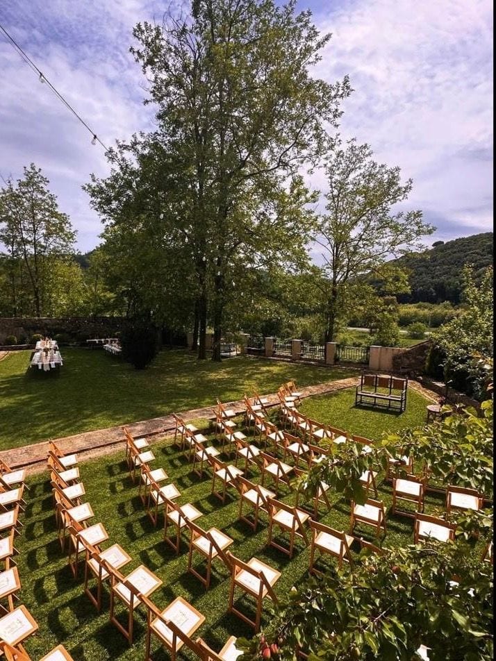 Jardín con mesas en hileras entre árboles